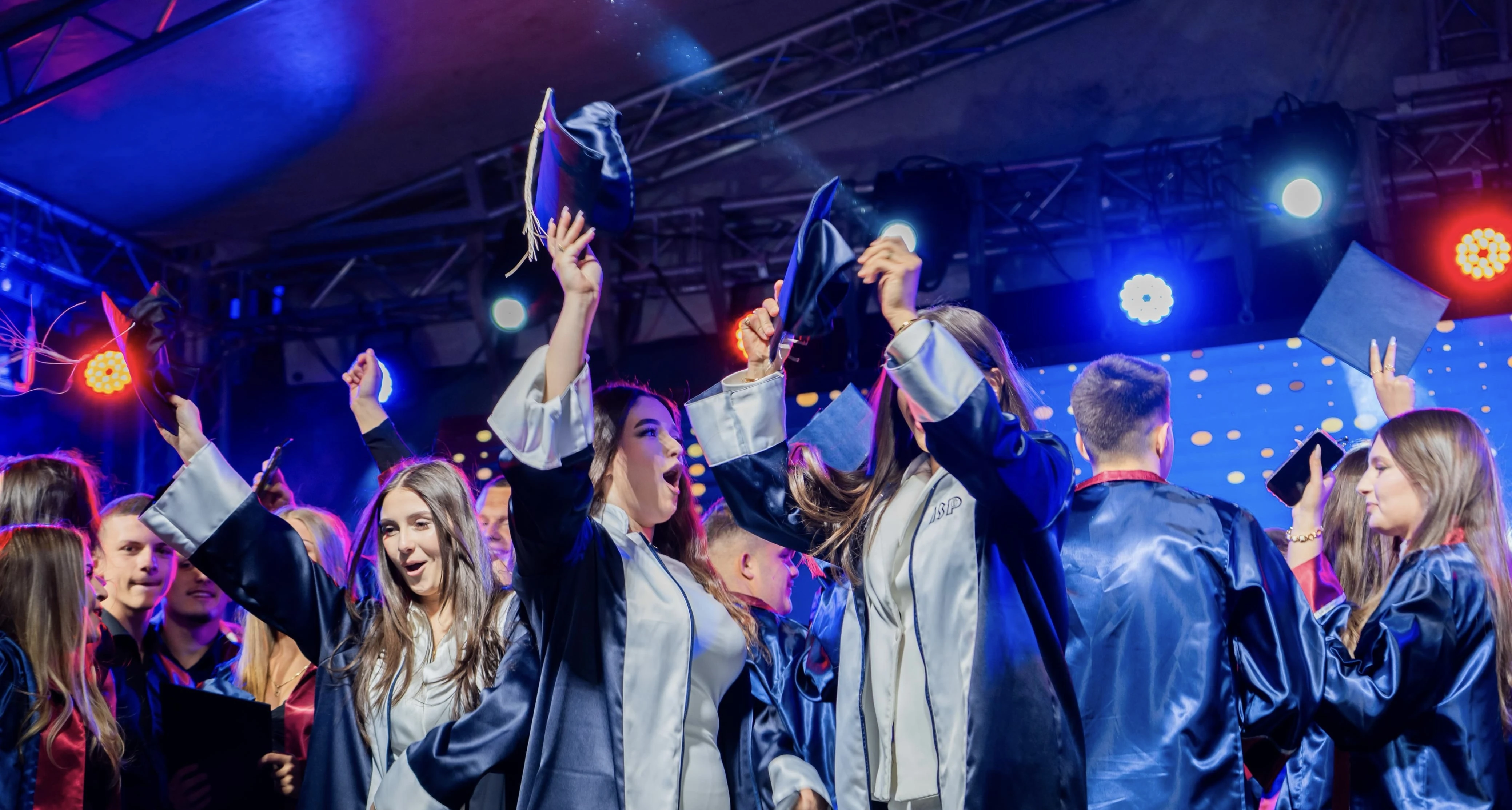 Gasten vieren op Afstudeerfeest onder blauwe en rode lichteffecten met confetti en rook