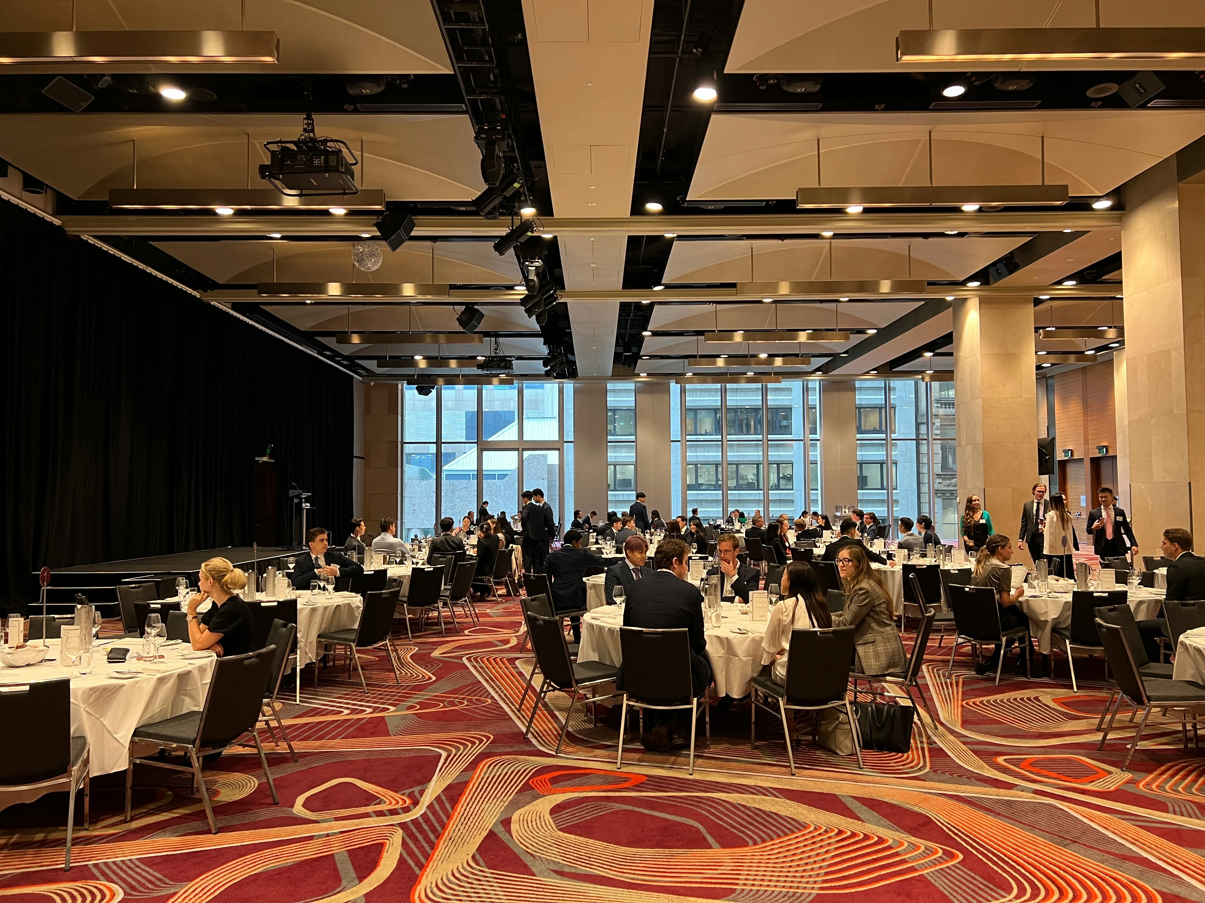 Guests dine at round tables in modern ballroom with large windows at Awards Night