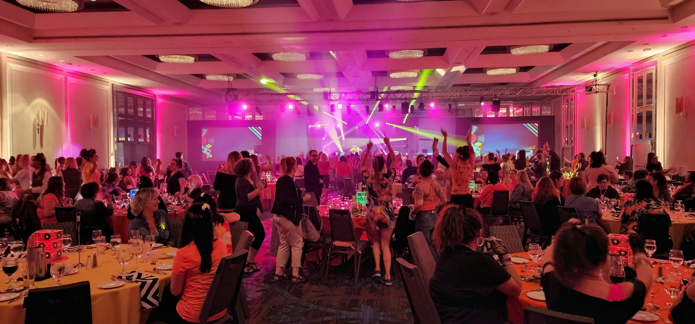 Guests celebrate at Awards Night with pink and green neon lighting, golden chandeliers and dance floor