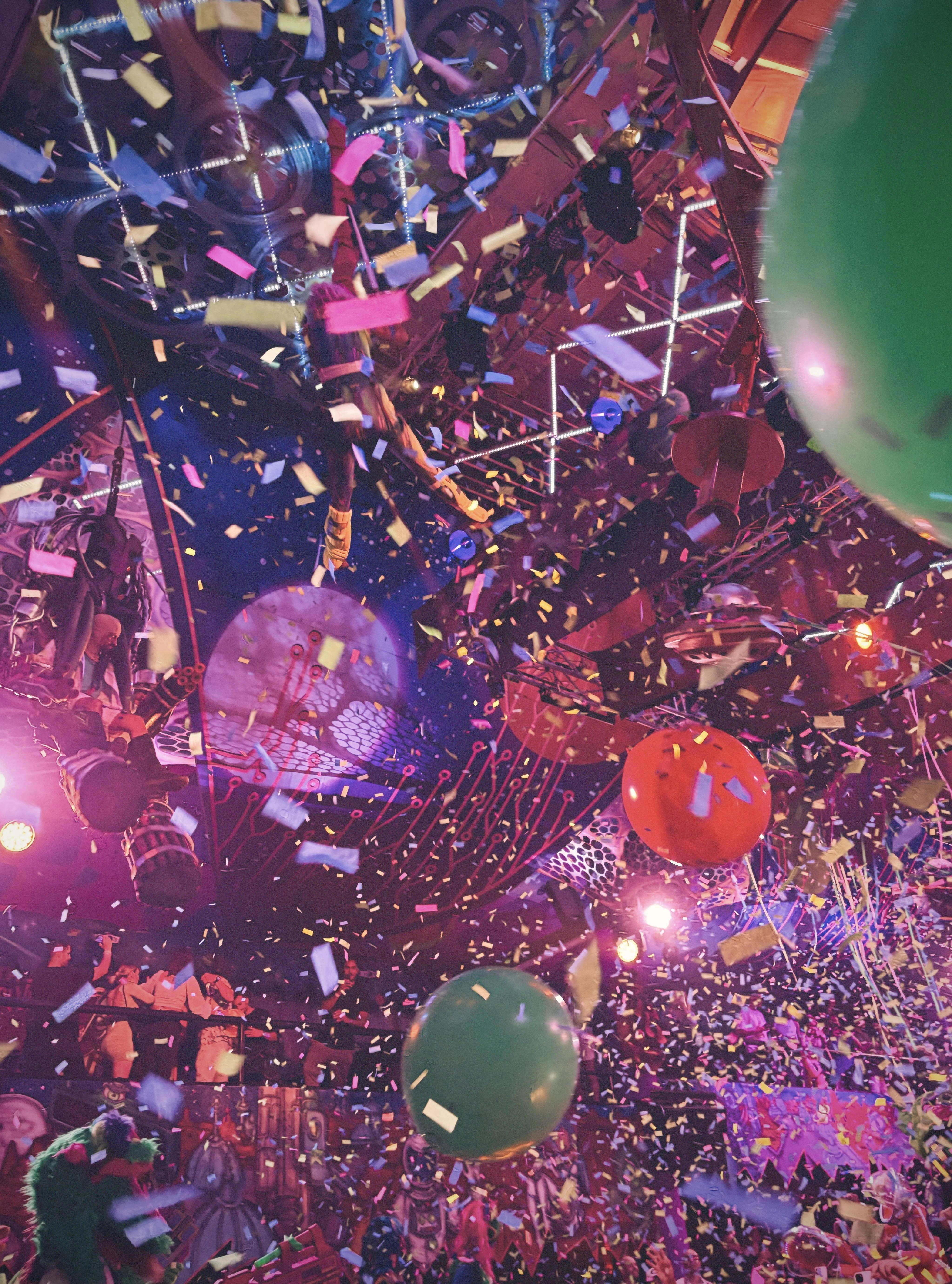 Feestelijk bedrijfsfeest met vallende confetti en ballonnen onder sfeervolle podiumverlichting in roze en paarse tinten