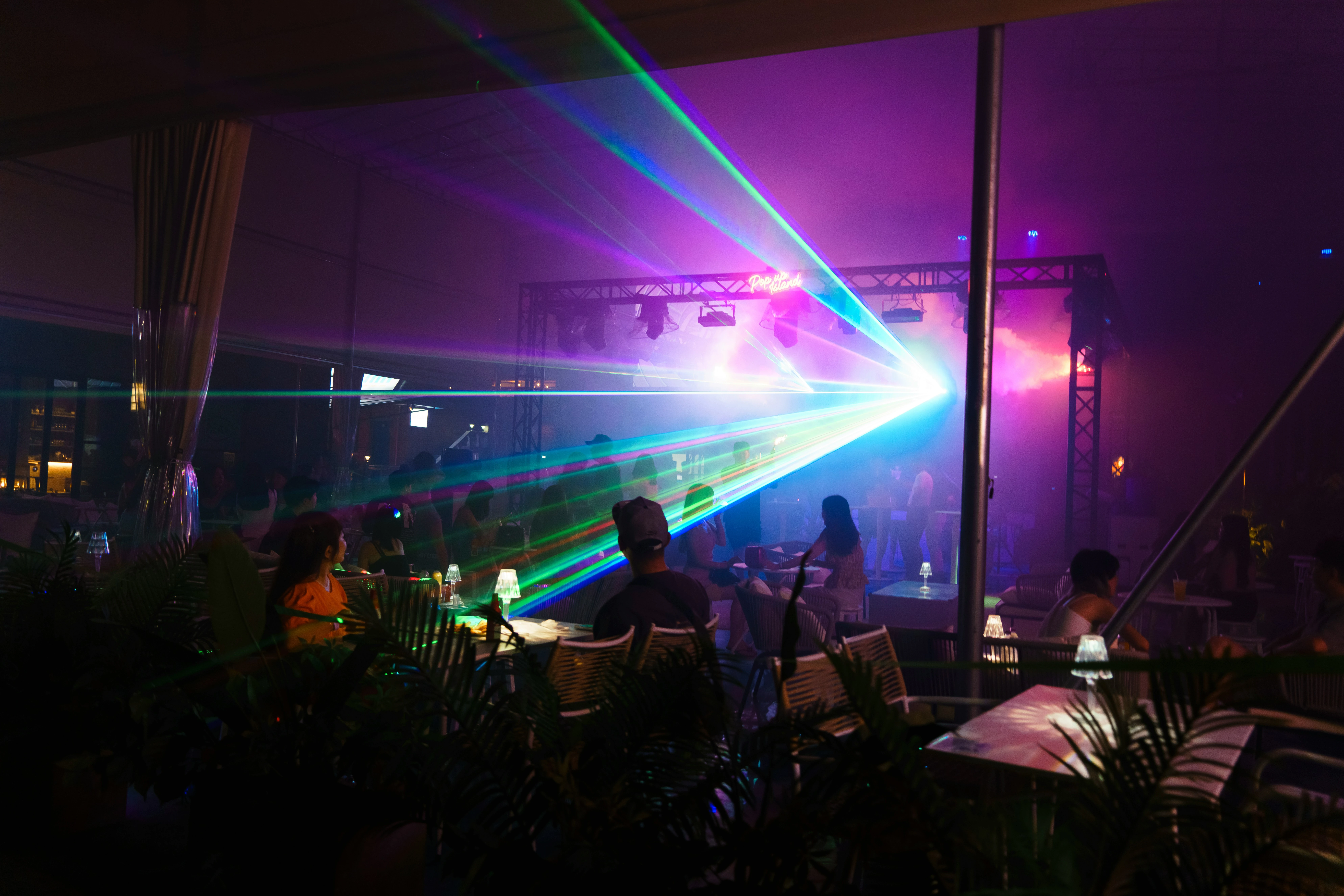 Crowd at company anniversary under purple and blue light beams and stage lighting