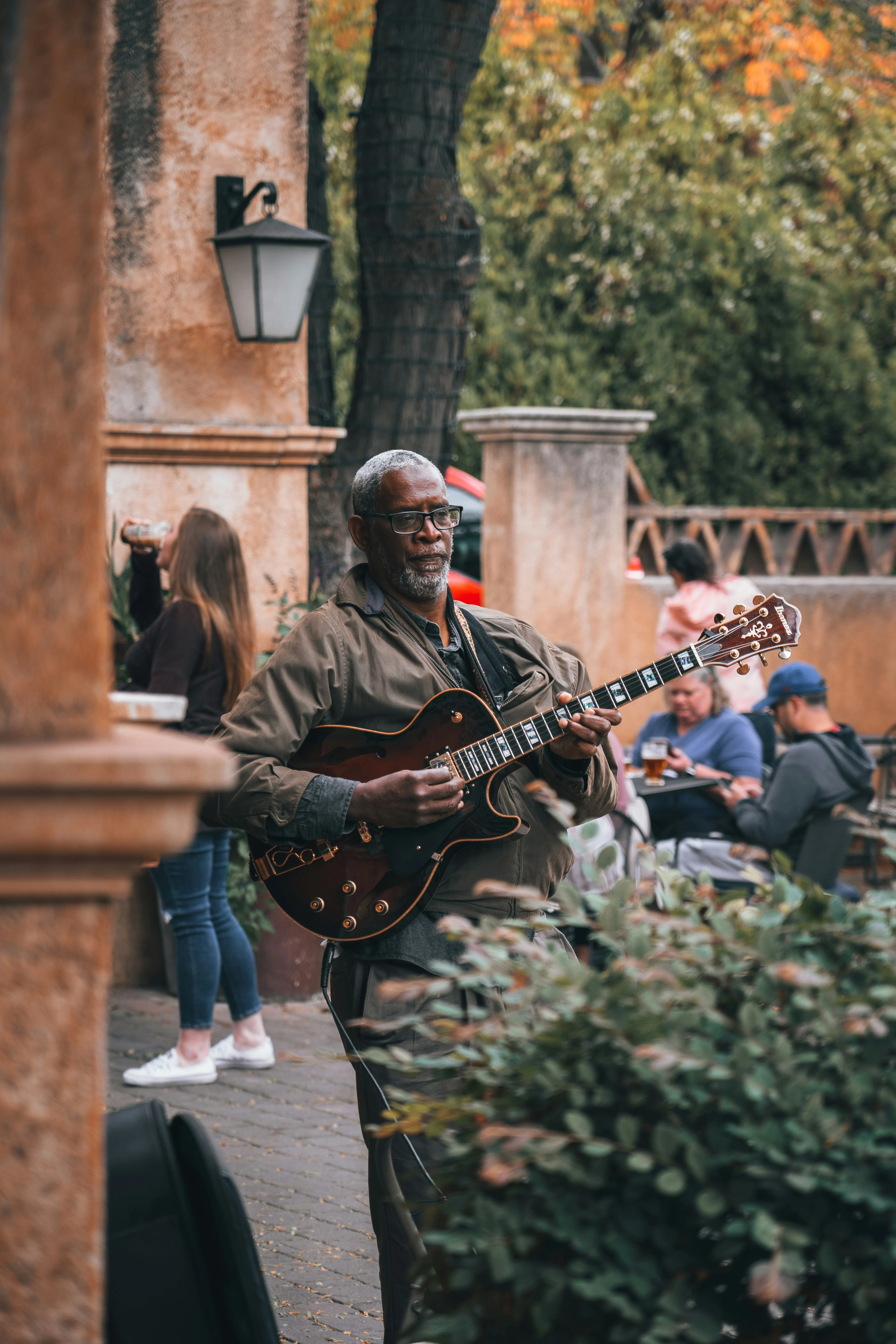 Straatmuzikant speelt gitaar op terras met publiek en historische architectuur op achtergrond