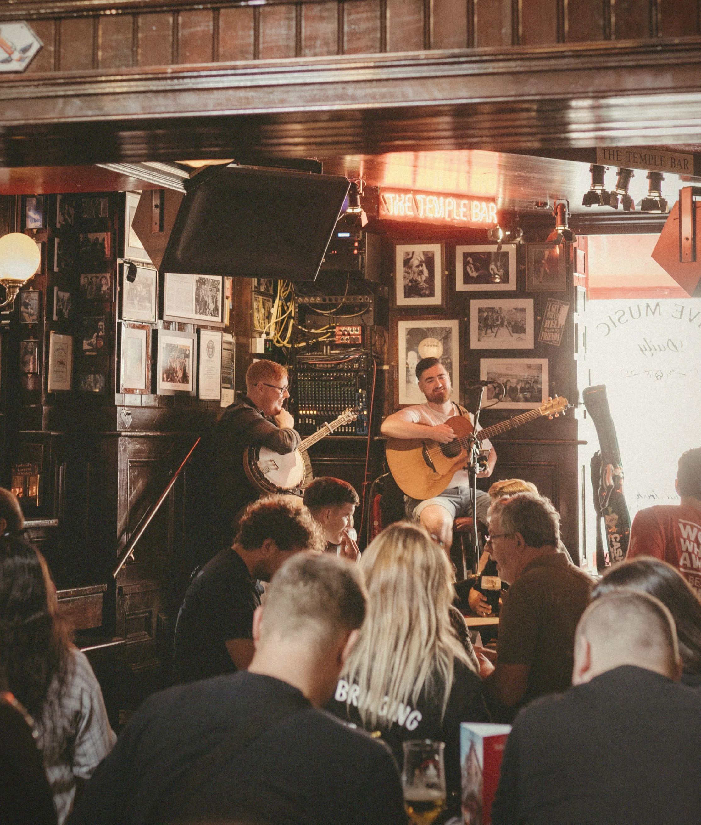 Twee muzikanten spelen banjo en gitaar tijdens livemuziek in traditionele pub met gasten