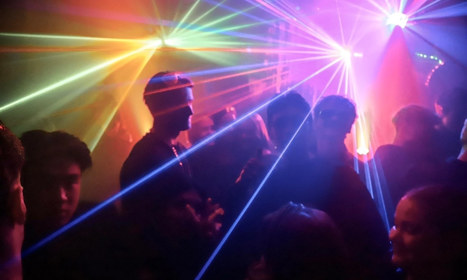 Menigte danst in nachtclub onder gekleurde laserstralen op gala