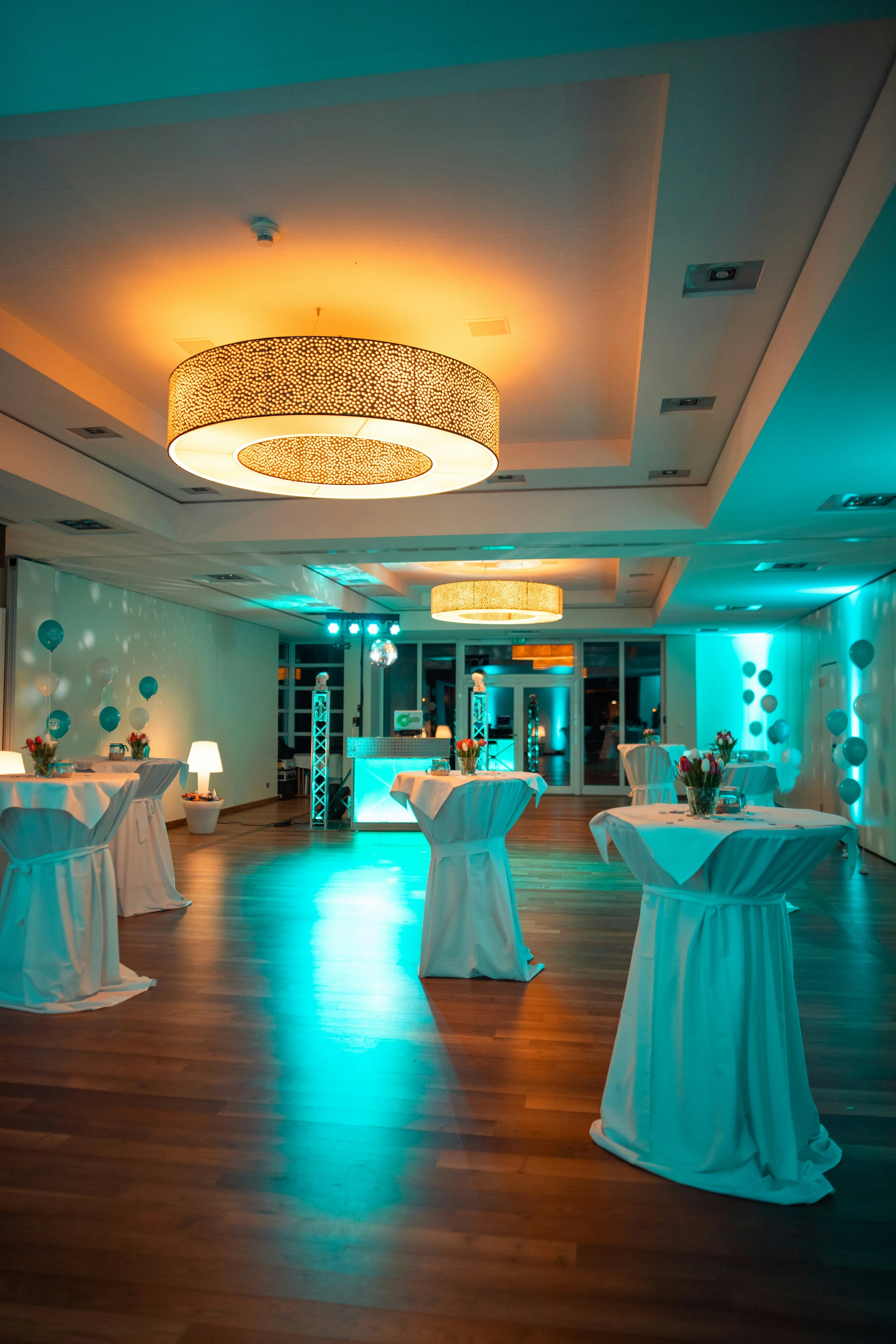 Moderne zaal op housewarming feest met gouden hanglamp en turquoise verlichting