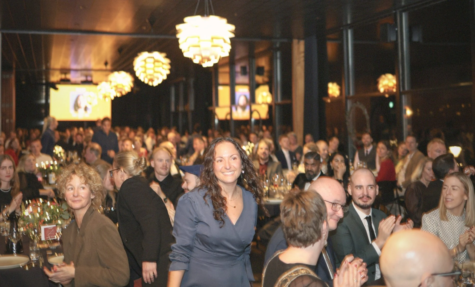 Sfeervolle zaal met vrouw in het midden en gasten die borrelend bij elkaar staan