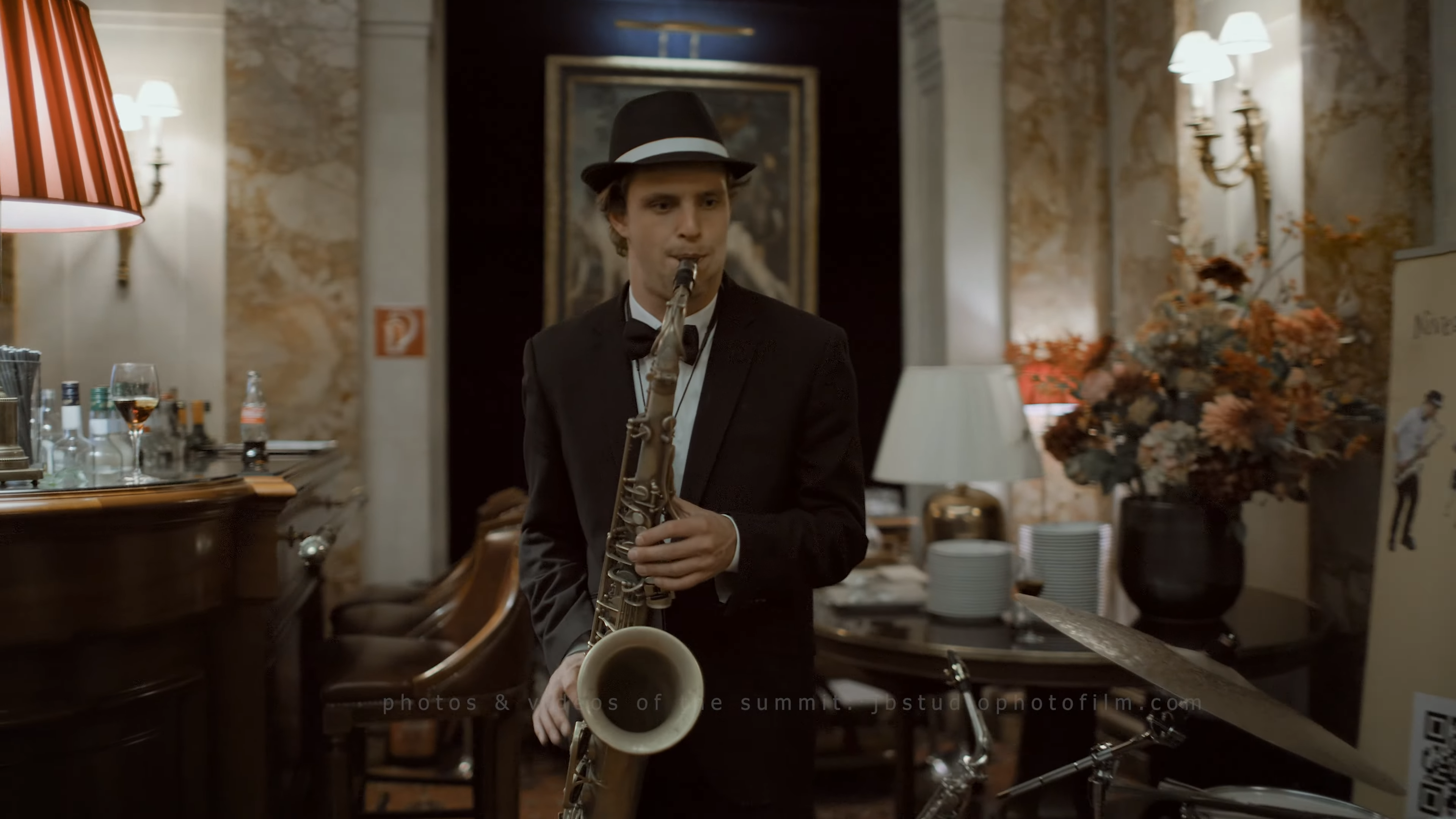 Saxofonist in pak en fedora speelt bij bar op kerstborrel