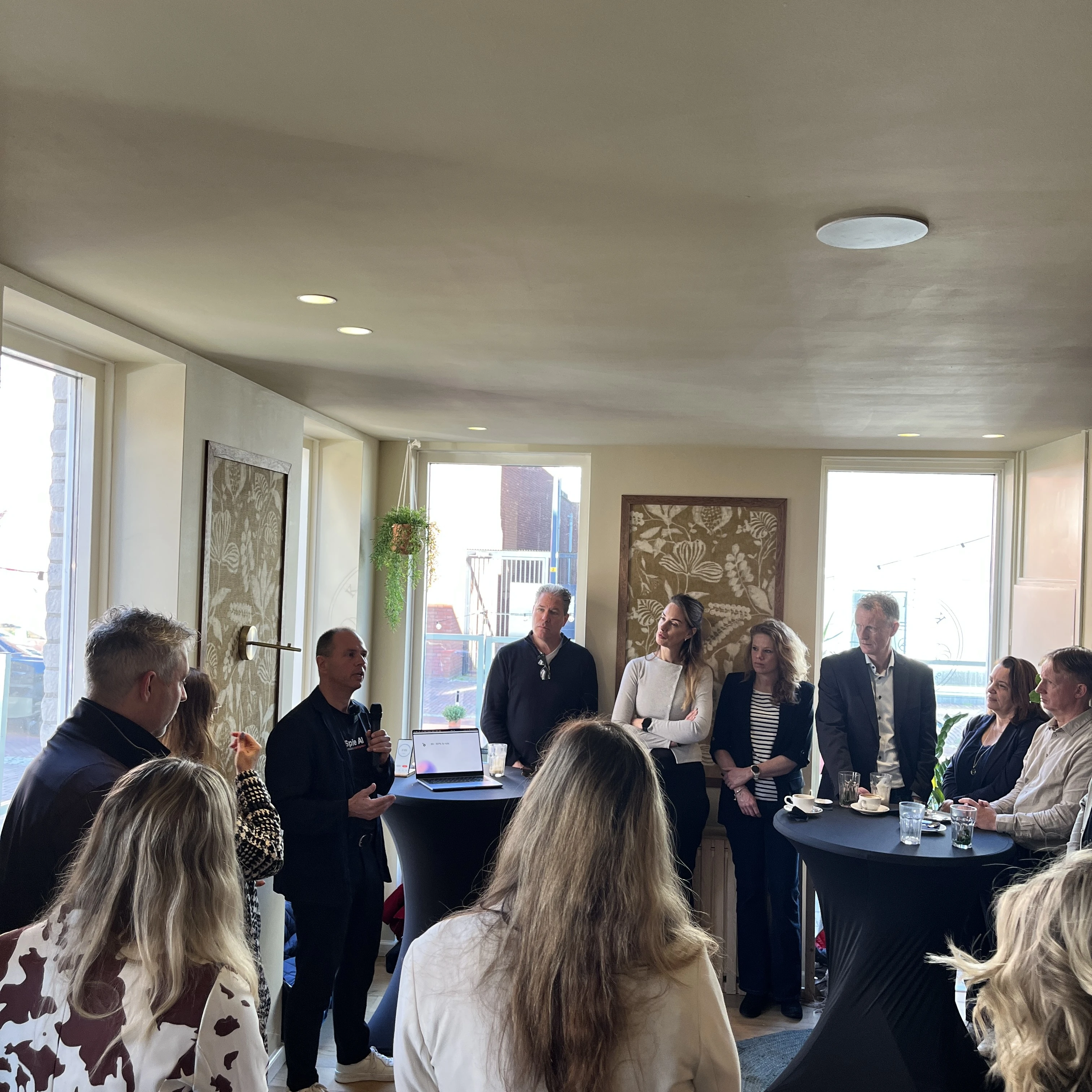 Speakers and guests stand together at customer appreciation day in modern office environment
