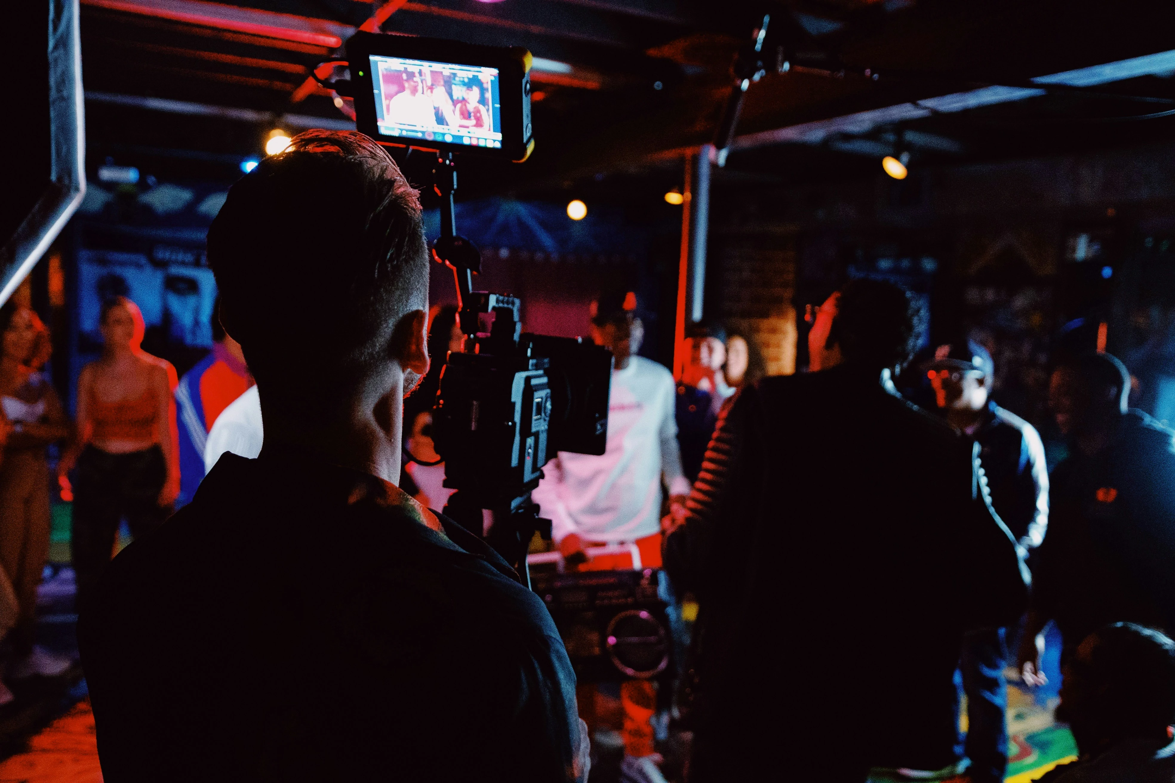 Cameraman filmt met professionele apparatuur tijdens productie op opening bedrijfspand onder rode en blauwe verlichting