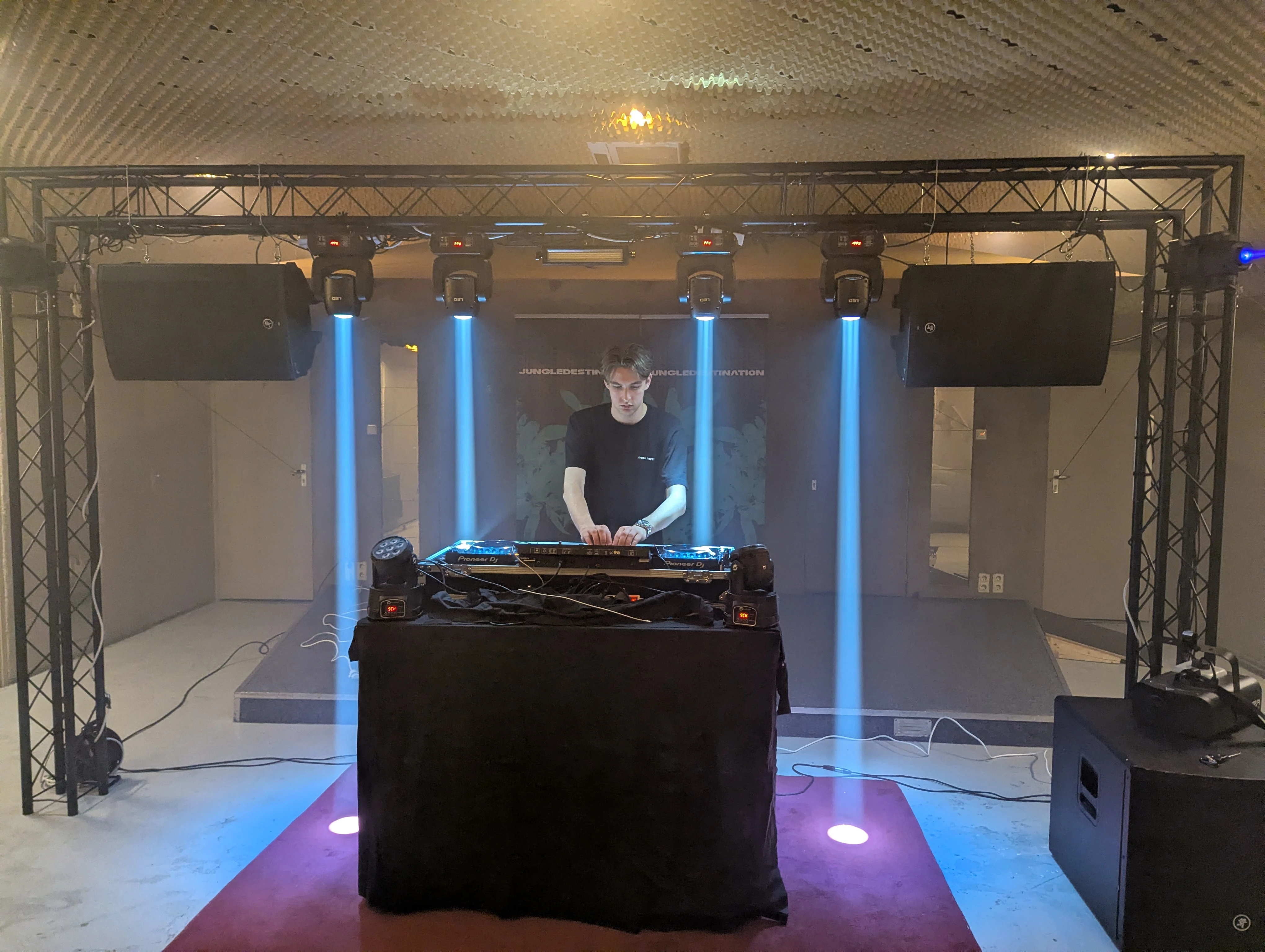 DJ-setup op podium voor opening bedrijfspand met trussconstructie, moving heads en luidsprekers