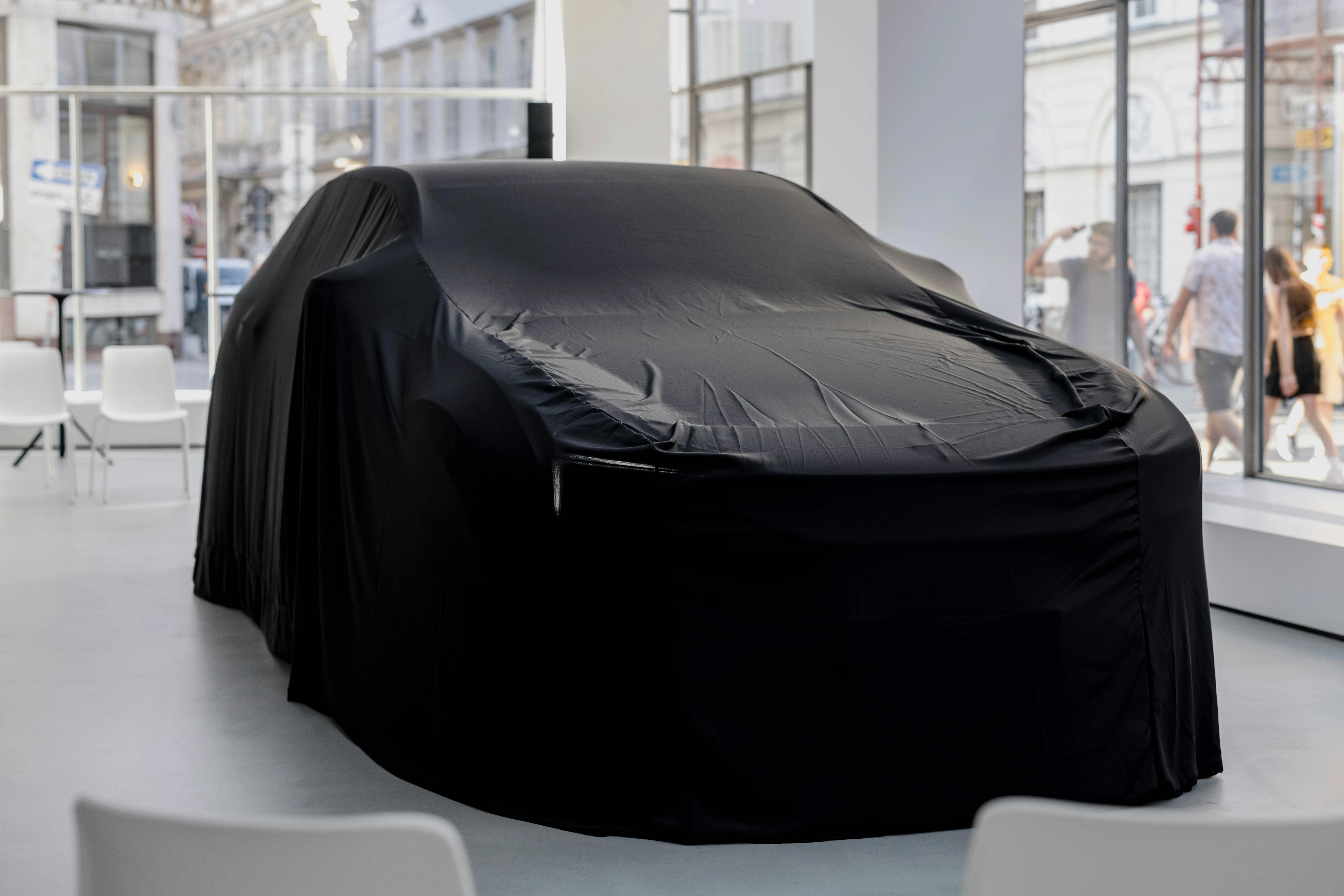 Auto onder zwart doek op podium op productlancering in moderne zaal
