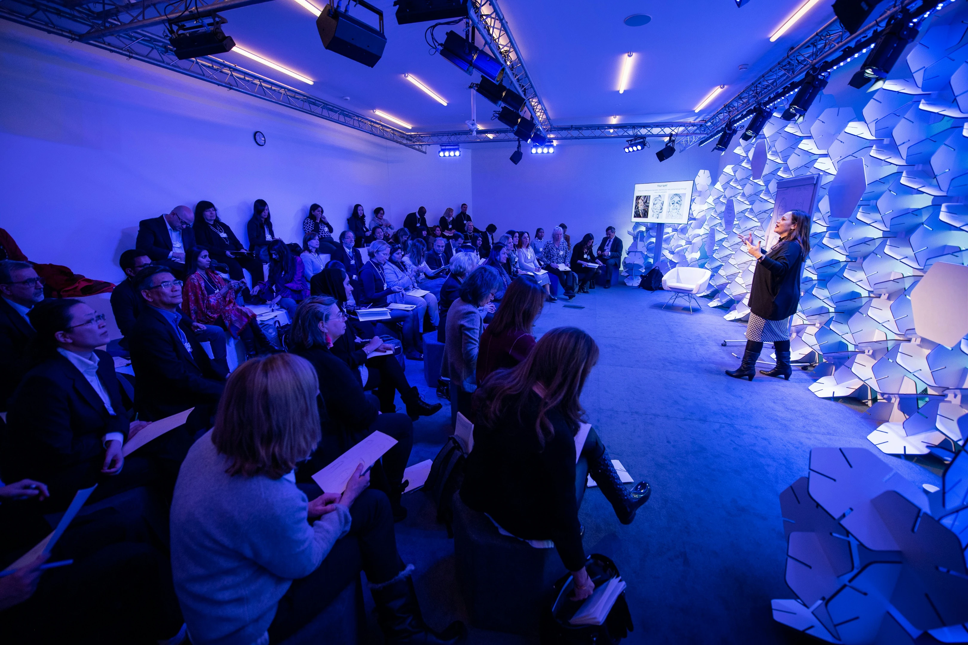 Bezoekers op productlancering onder blauwe verlichting met groot videoscherm