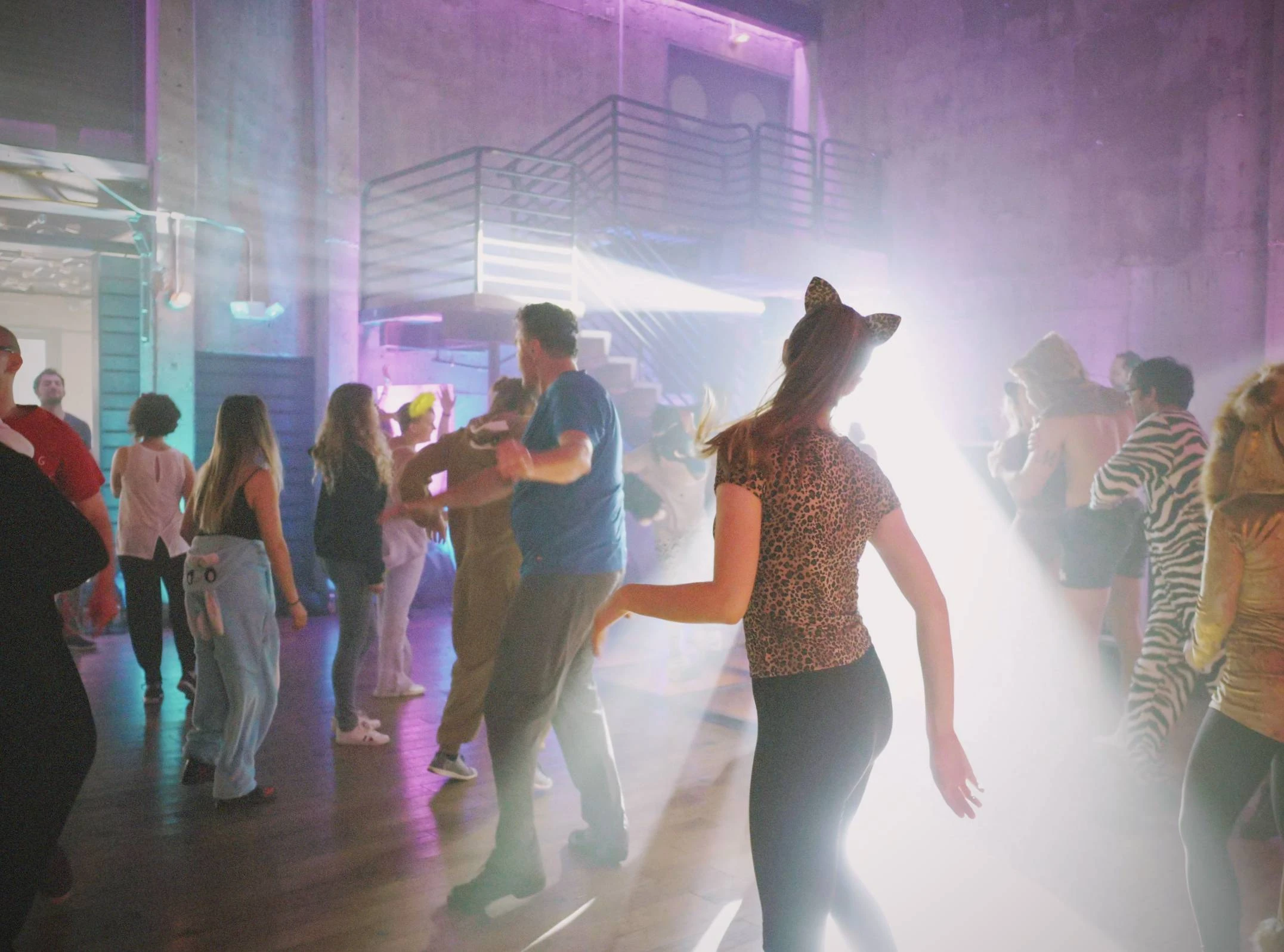 Vrouw danst op themafeest in verkleding, lichtstraal schijnt door haar heen