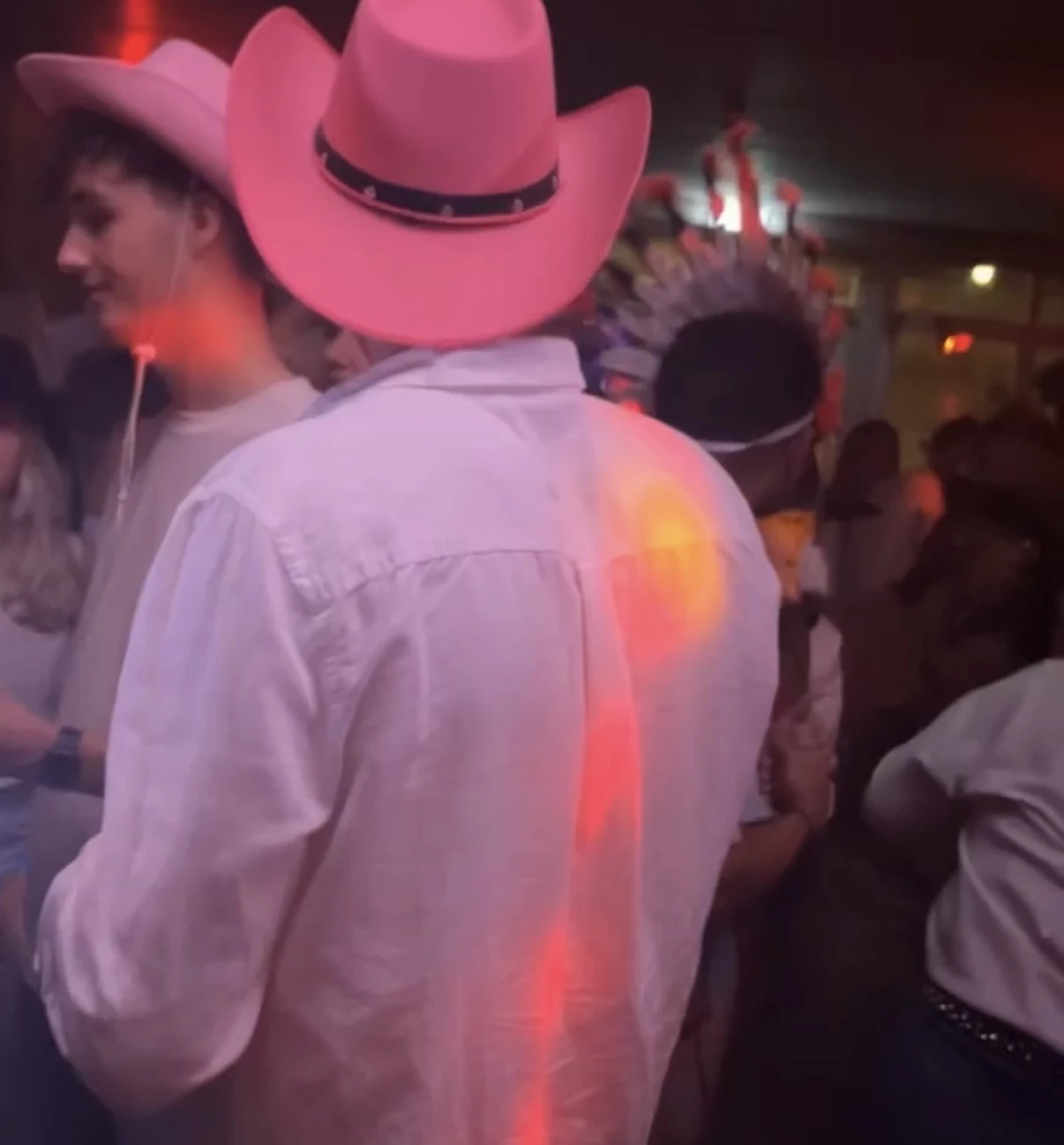Jongen met cowboyhoed omringd door mensen in westers kostuum op een themafeest