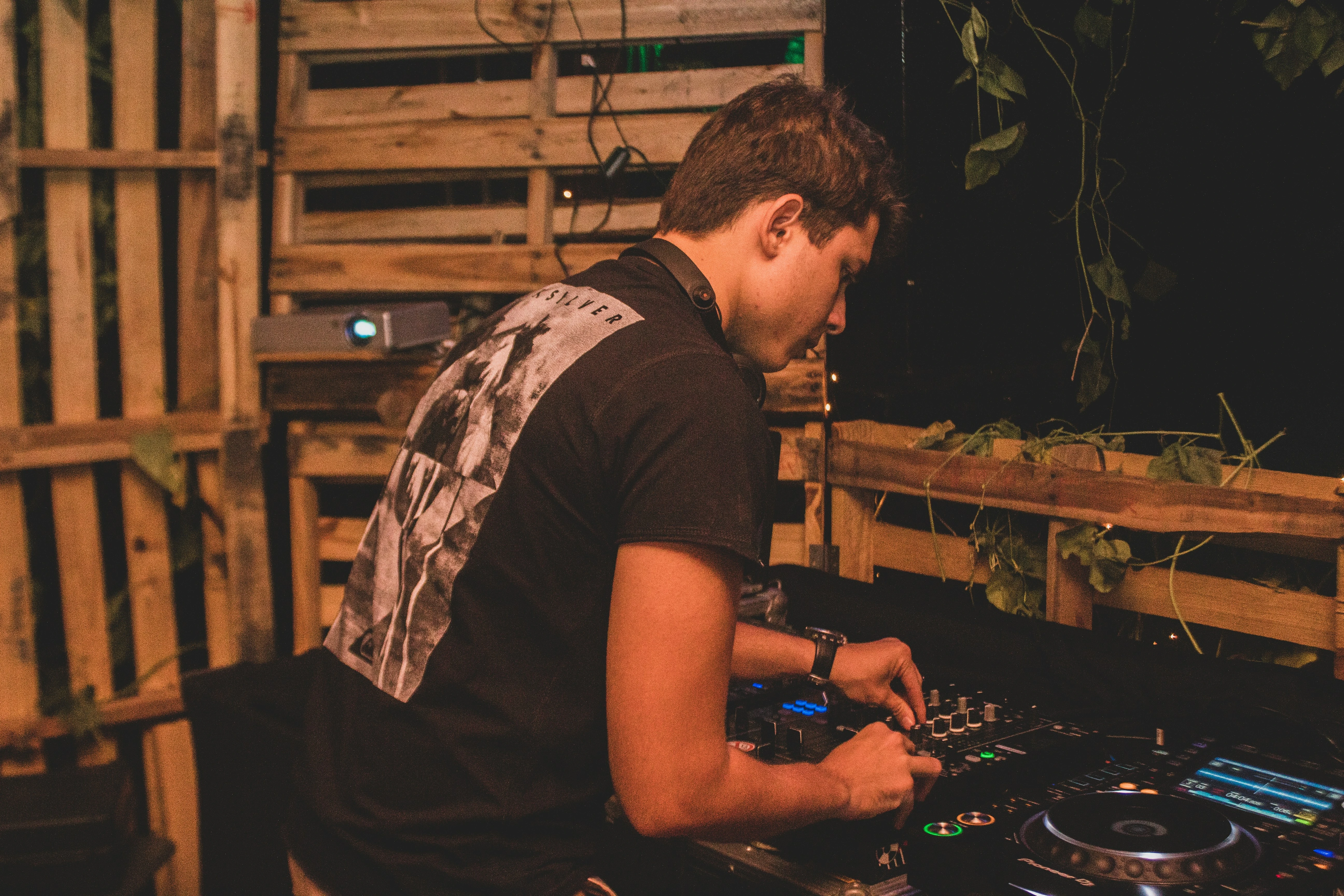 DJ draait op houten podium op tuinfeest met warm licht en groene planten