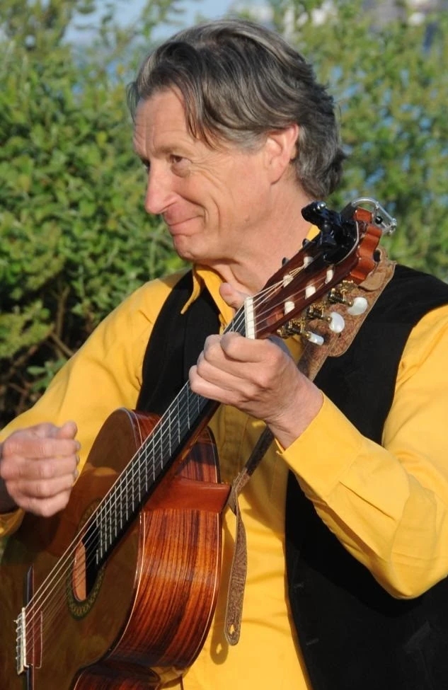 Muzikant speelt akoestische gitaar op tuinfeest tegen groen gebladerte